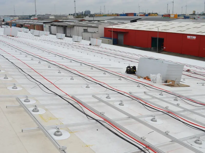 Plat bedrijfsdak met aluminium montagerails en kabels, klaar voor de montage van zonnepanelen