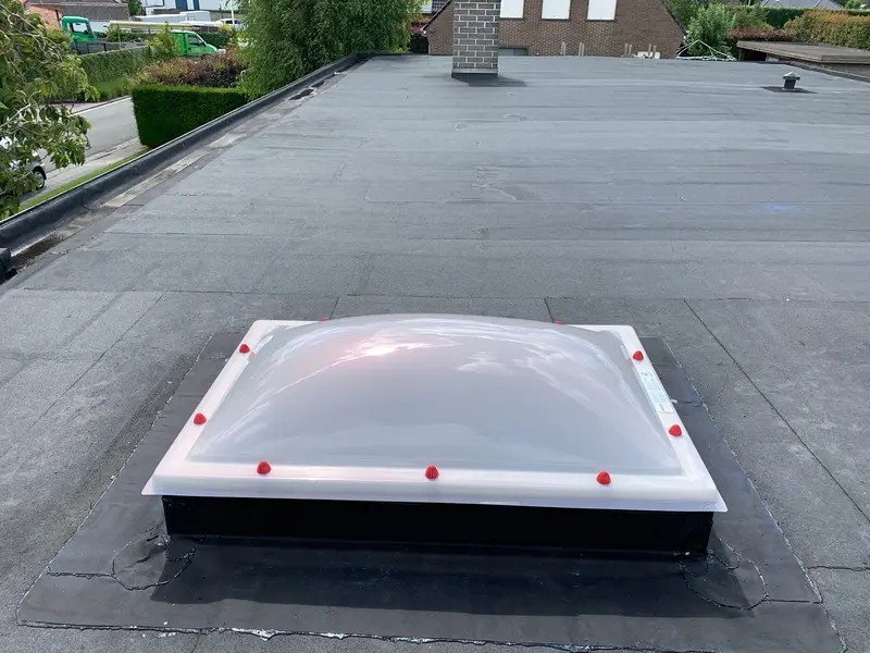 Bolle lichtkoepel in opaal kunststof op een plat dak met bitumen