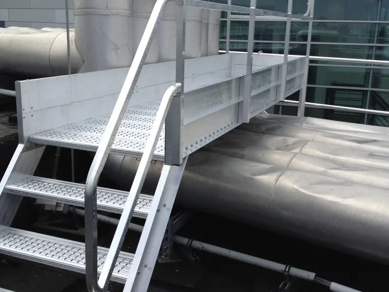 Aluminium trap en loopbrug met leuningen over buizen op een plat dak
