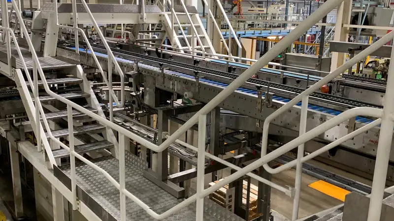 Witte trappen en bordessen boven een productielijn in een fabriek