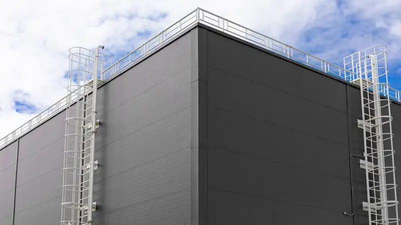 Grijze gevel van wandpanelen met twee kooiladders