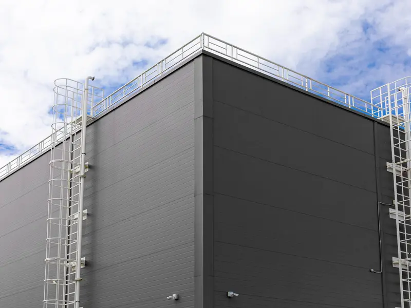 Grijze gevel van wandpanelen met twee kooiladders