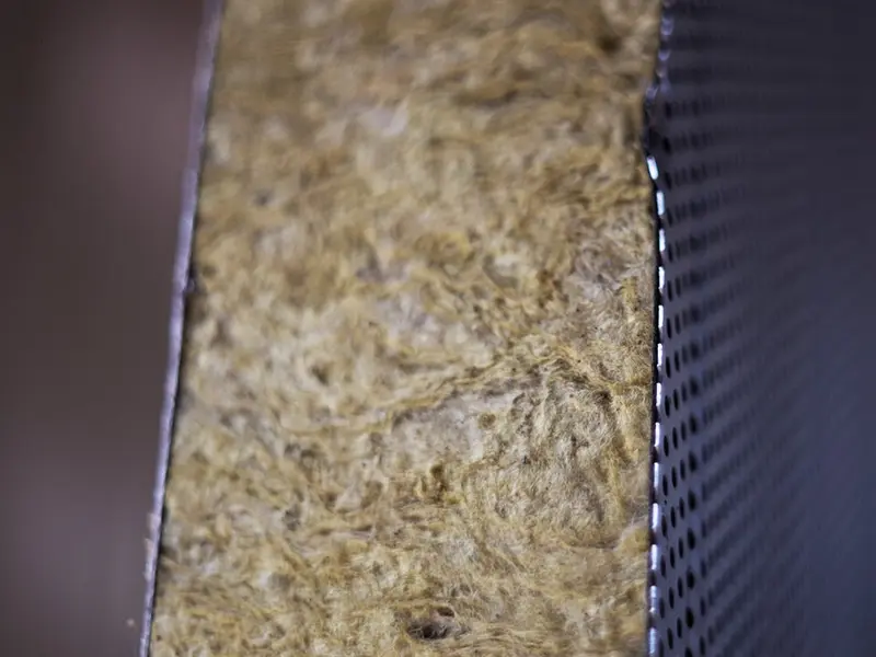 Close-up van de steenwolkern van een sandwichpaneel naast een geperforeerde metalen plaat